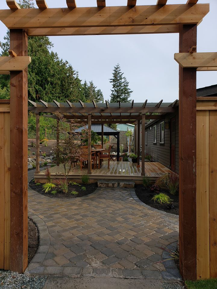a wooden archway leading to a patio with a pergola and umbrellas