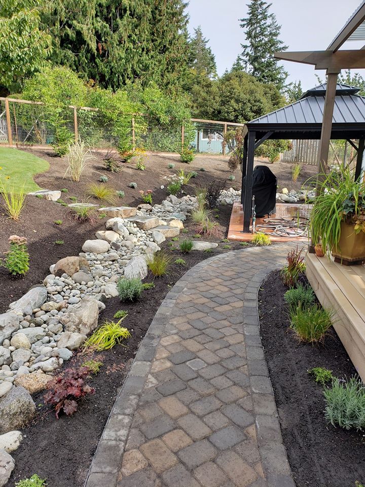 a brick walkway leading to a gazebo in a garden .