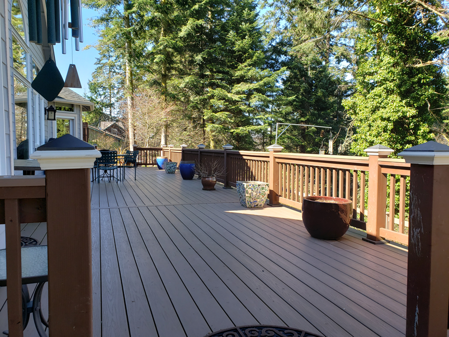 a large wooden deck with a fence and potted plants on it .