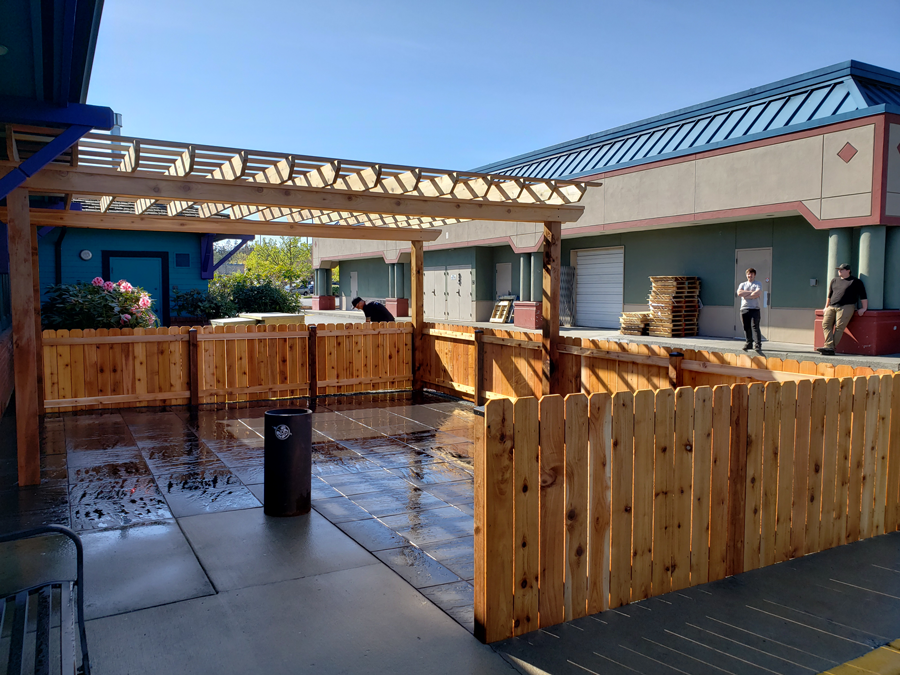 a wooden fence is surrounding a patio in front of a building .