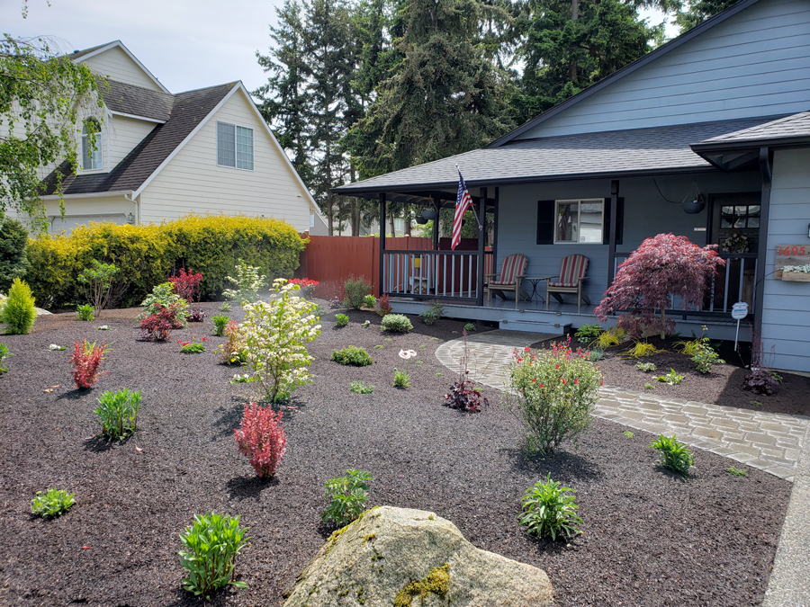 a house with a porch and a garden in front of it .
