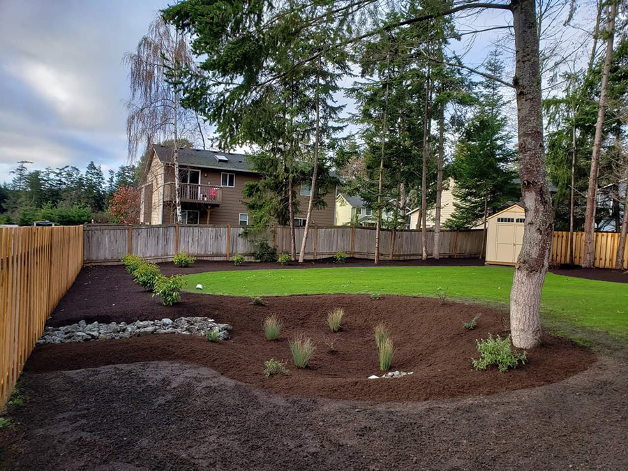 a backyard with a wooden fence and a house in the background .