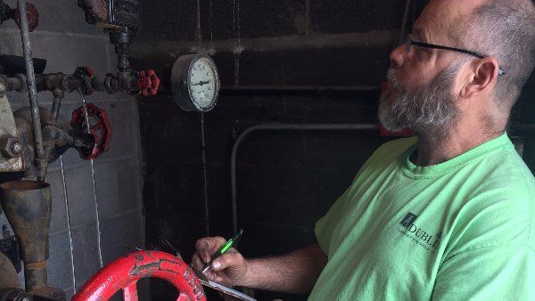 Commercial Property Inspection Services. A technician with a clipboard, reading a meter.