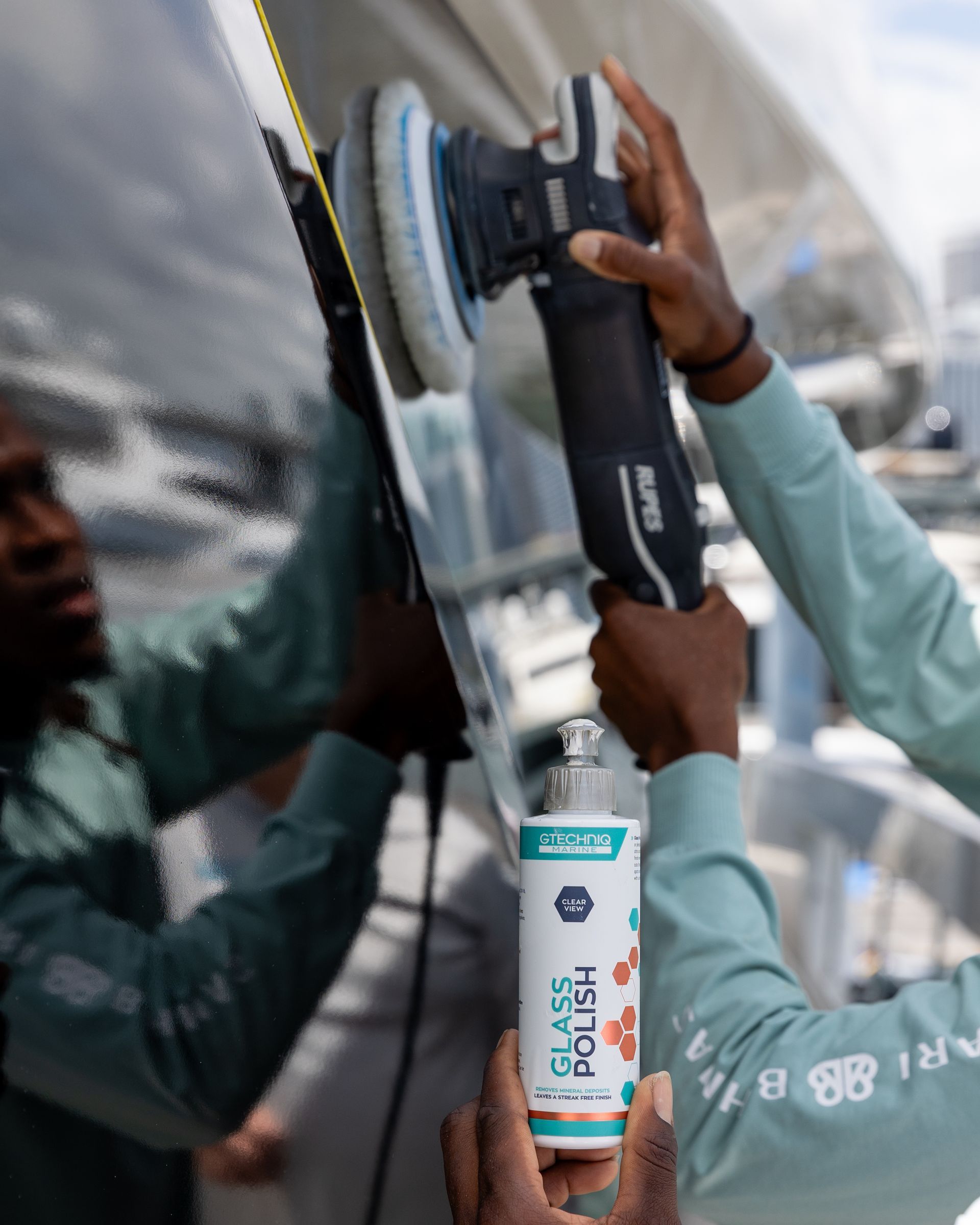 Workers polishing a vehicle with a power buffer in a car wash bay