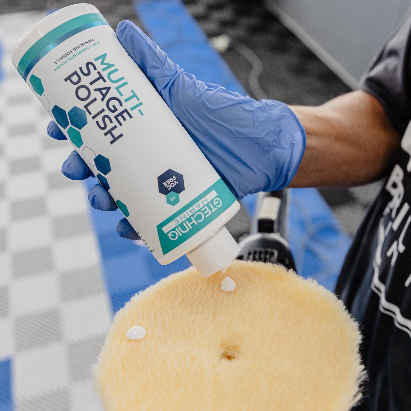 Person applies white stain polish to a tan cushion with a blue-gloved hand.