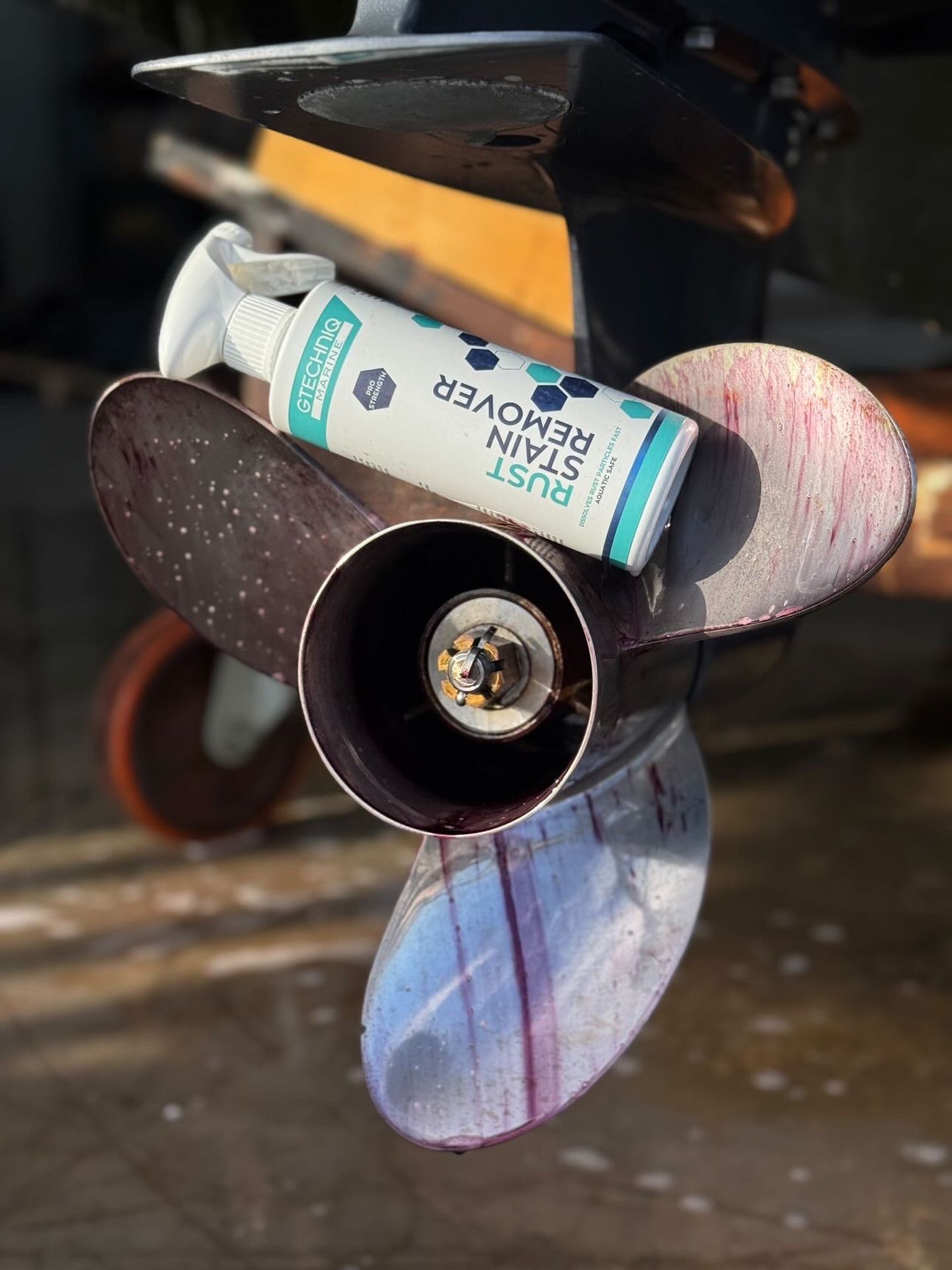 Close-up of a small propeller with a toothpaste tube attached, on a dark surface outdoors.