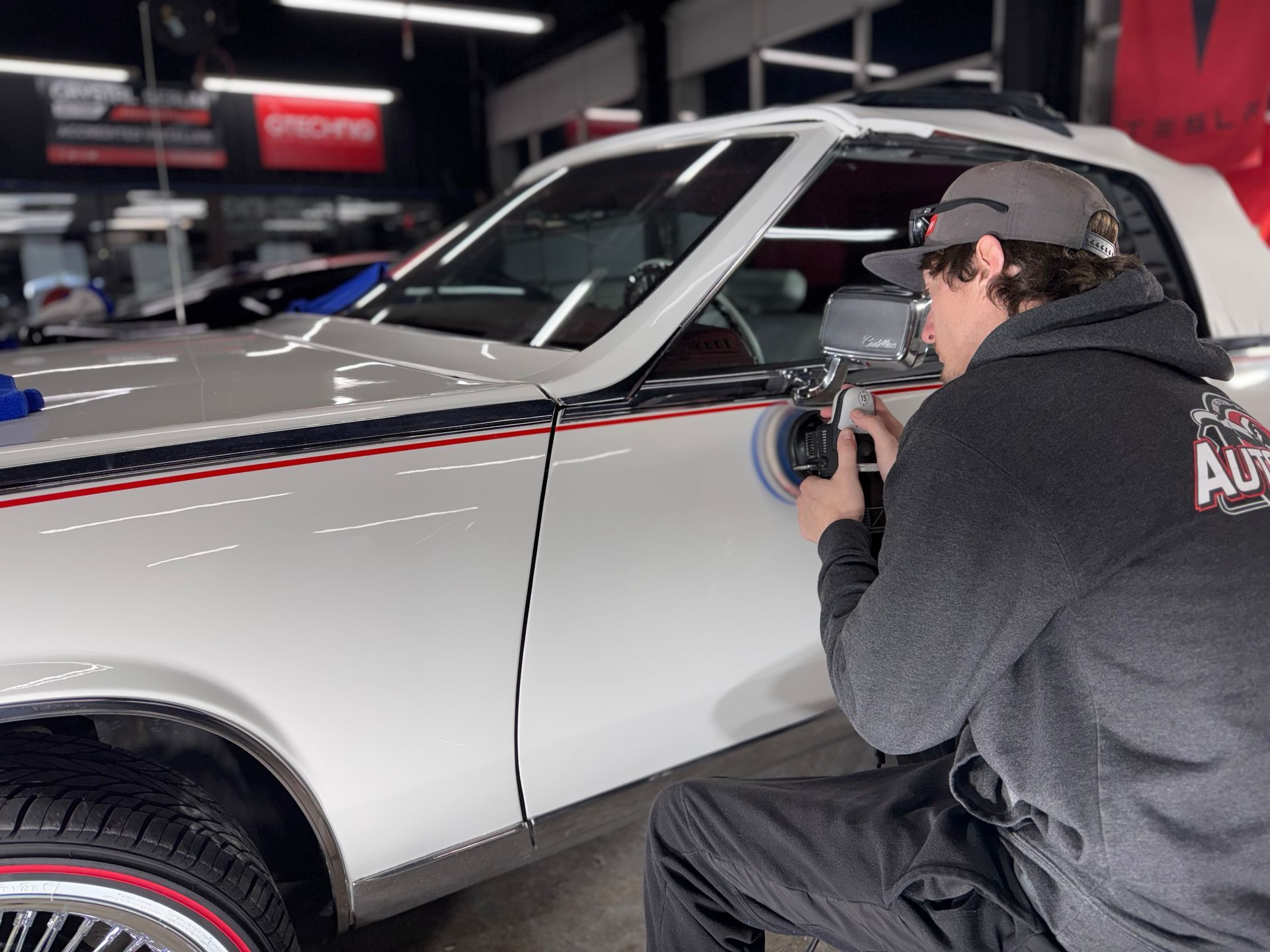 A man is polishing a white car in a garage.