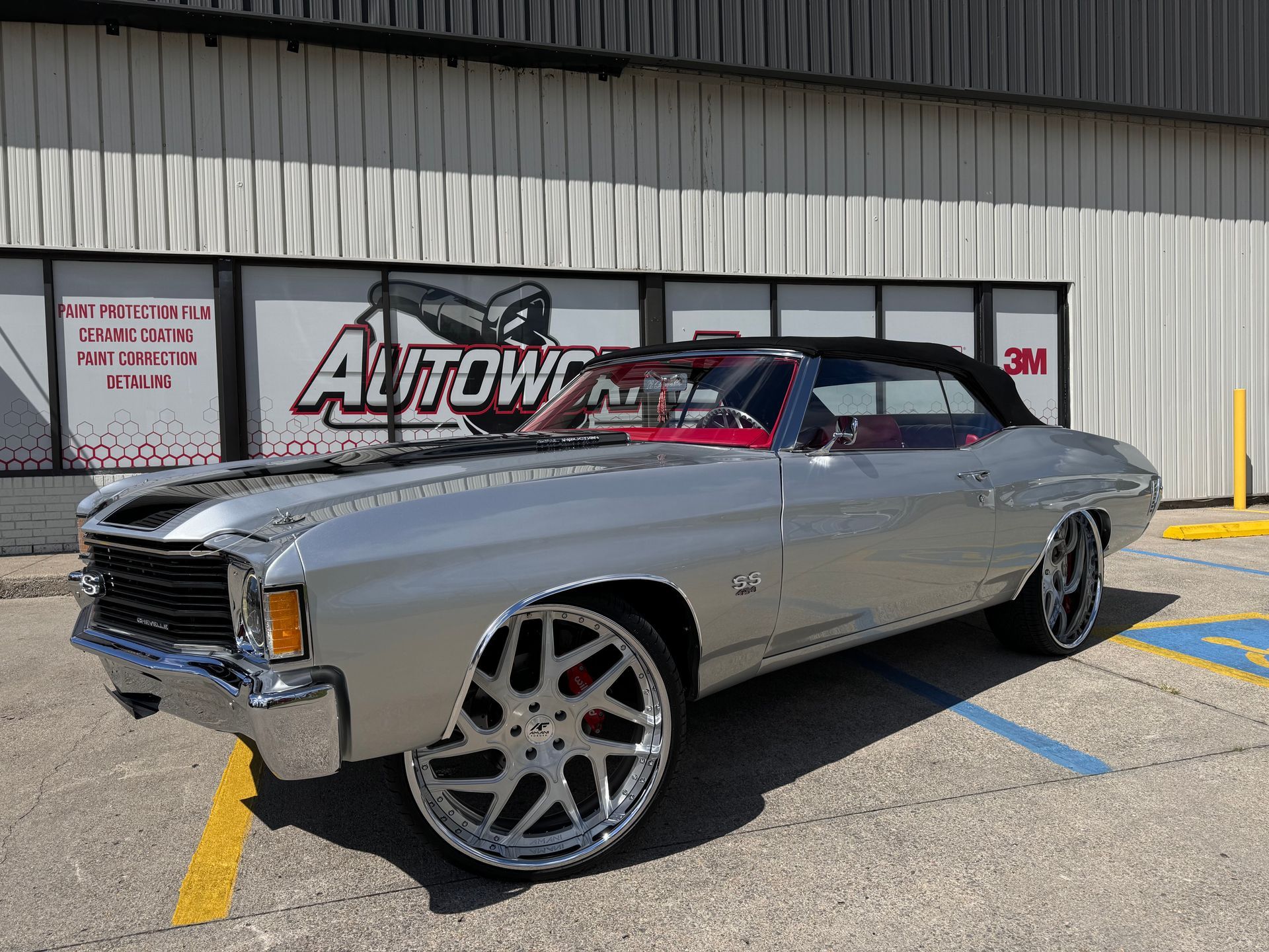 A silver car is parked in a parking lot in front of a building.