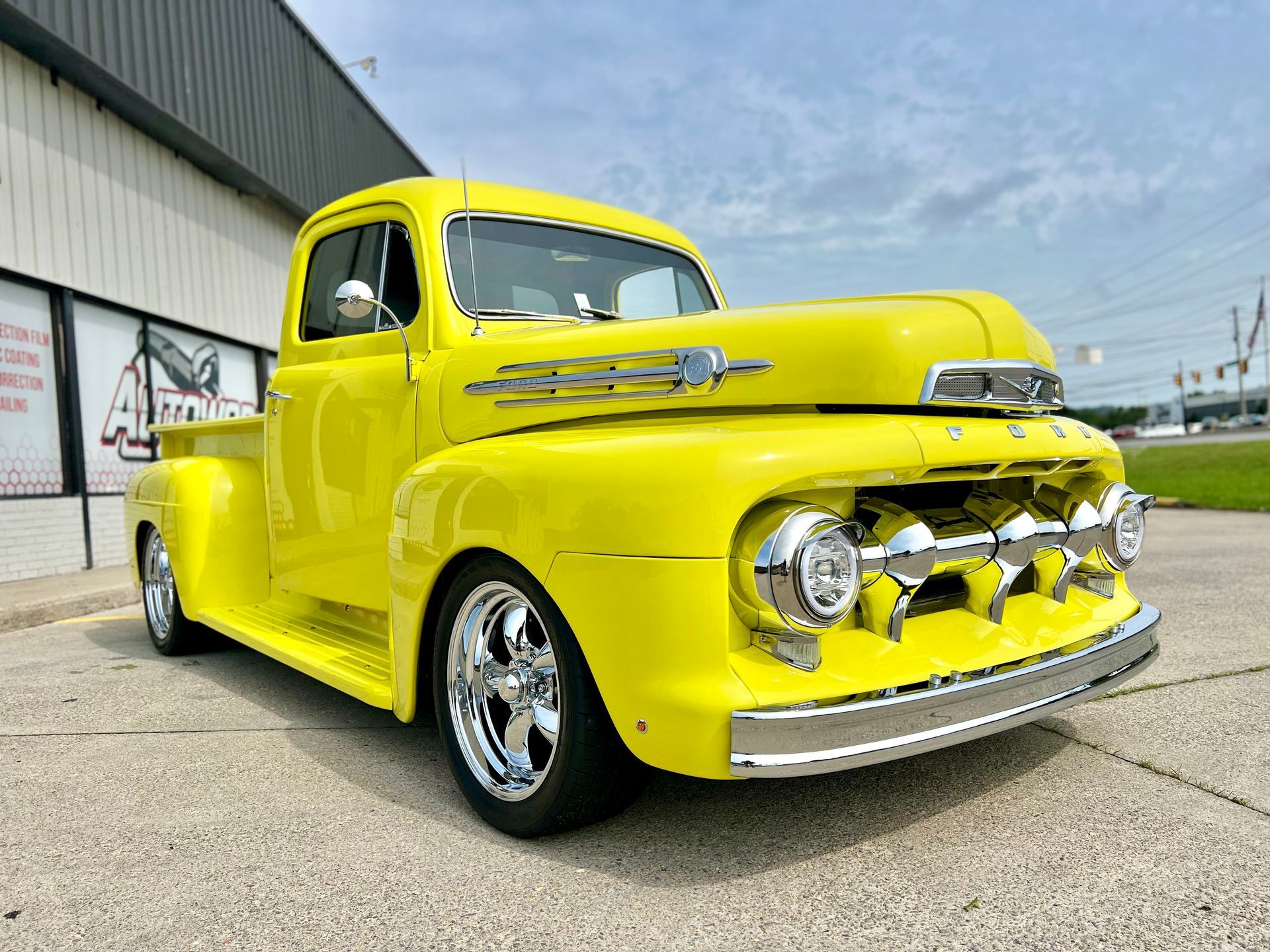 A yellow pickup truck is parked in front of a building.