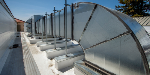 A row of metal pipes on the roof of a building.