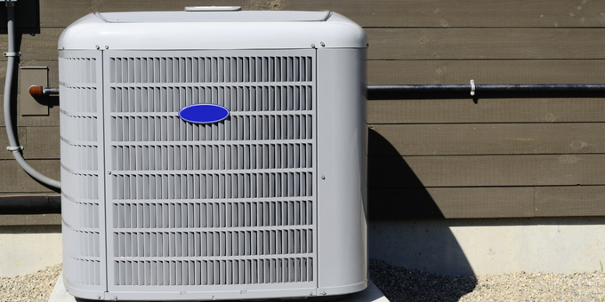 A carrier air conditioner is sitting outside of a building.