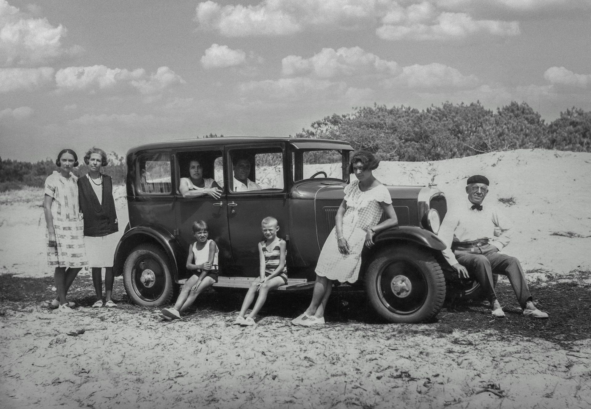 old picture of people in front of a car