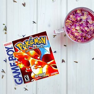 A game boy game is on a table next to a cup of tea