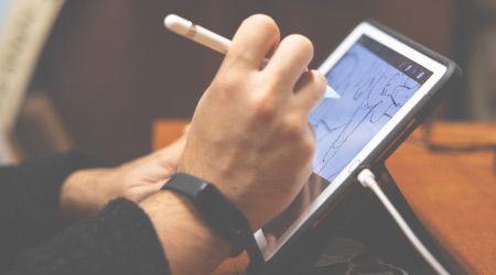 A person is writing on a tablet with a pen.