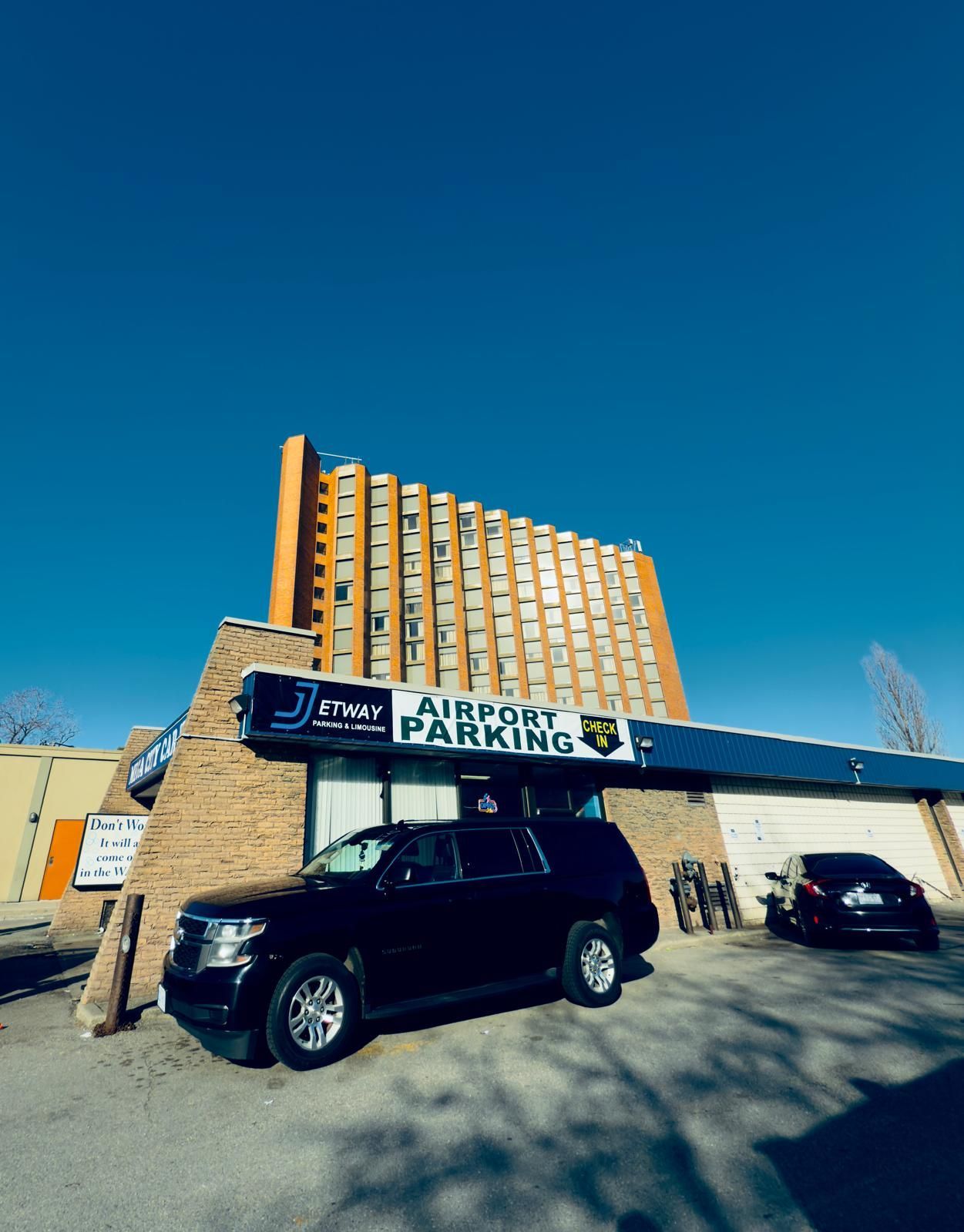 A black suv is parked in front of a building that says airport parking
