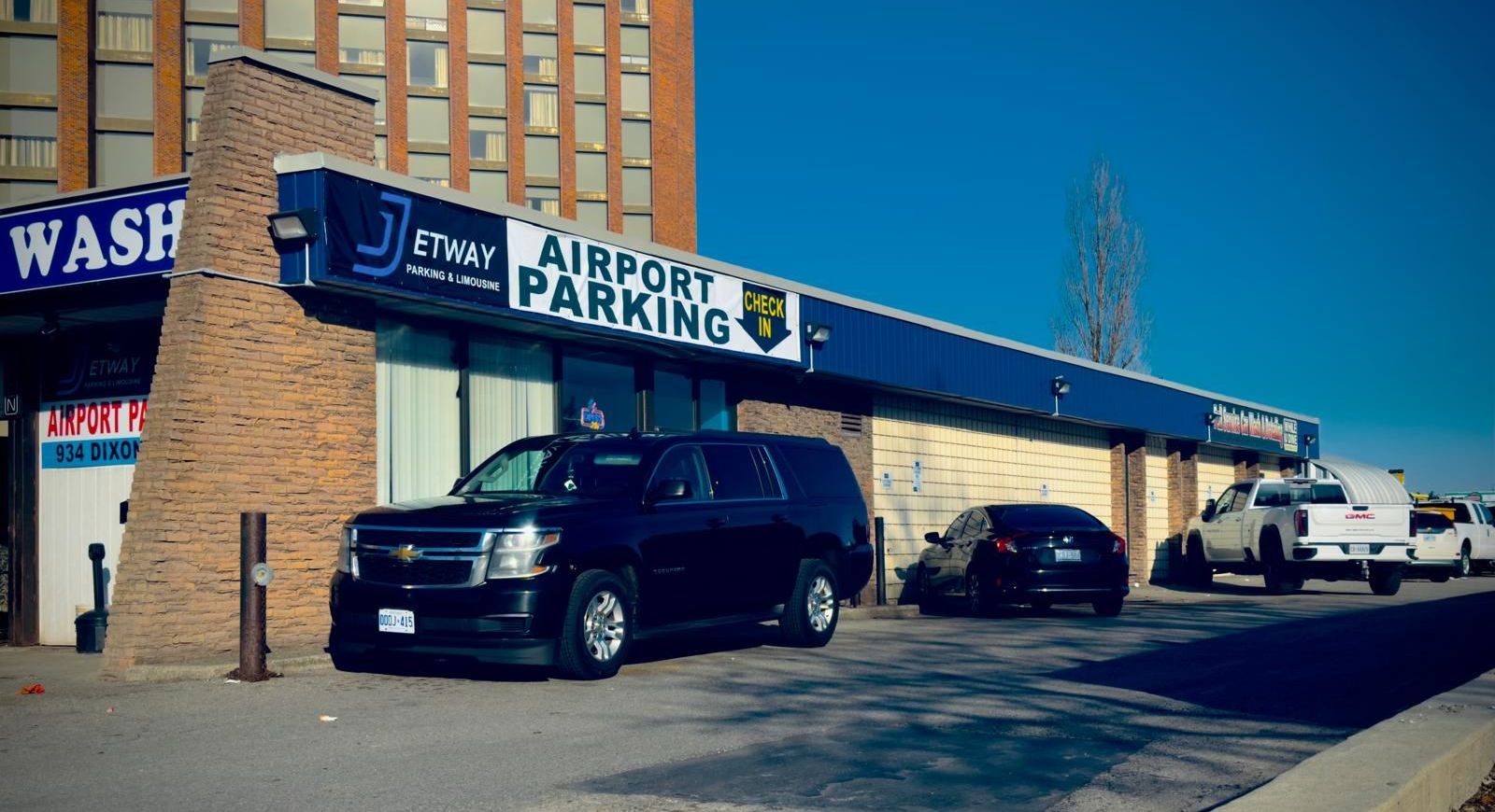 A black suv is parked in front of a building that says jetway airport parking