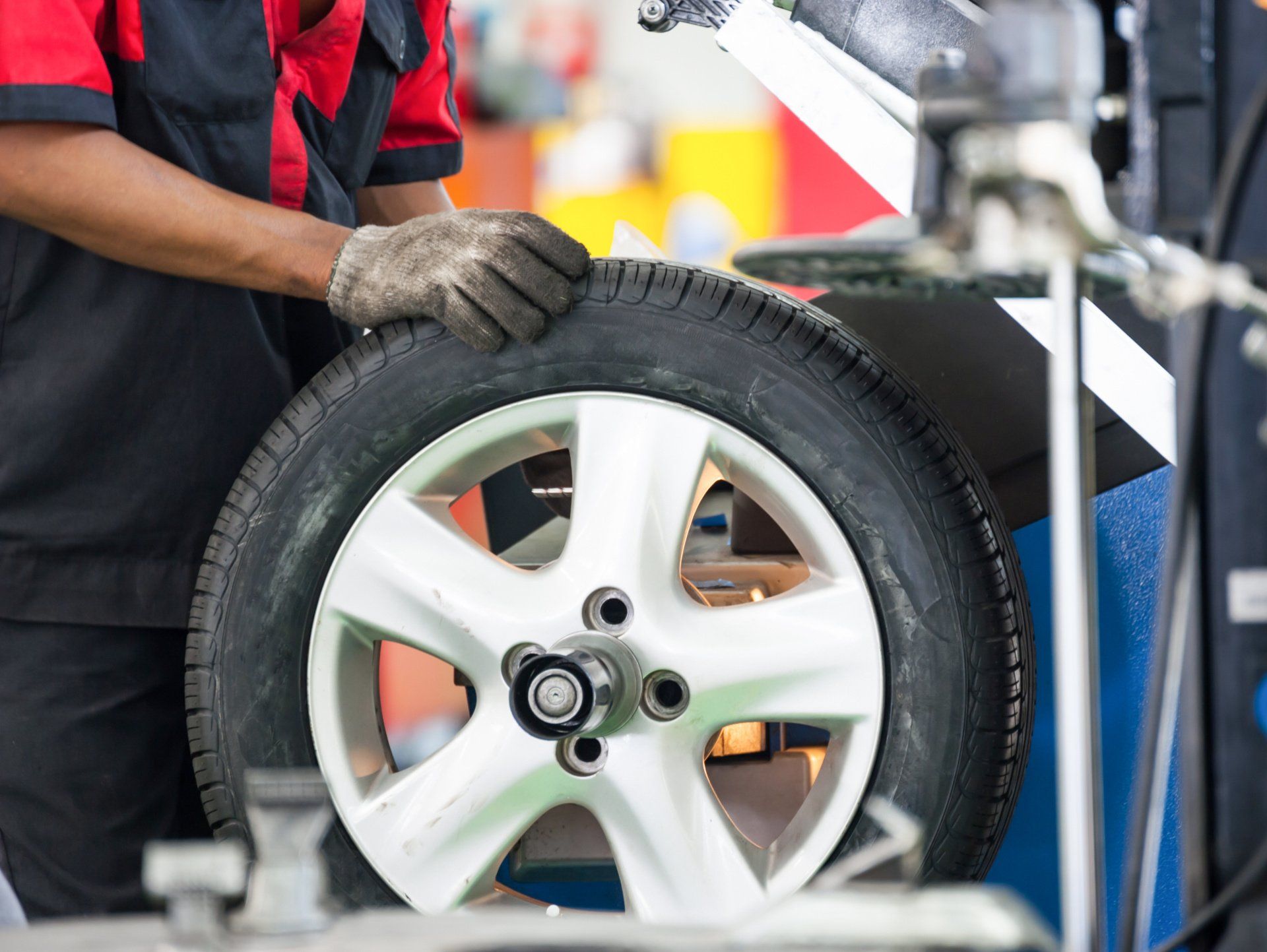 A man is changing a tire on a car in a garage.