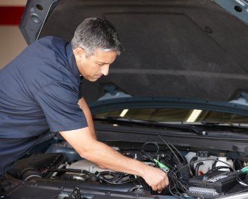 A man is working under the hood of a car