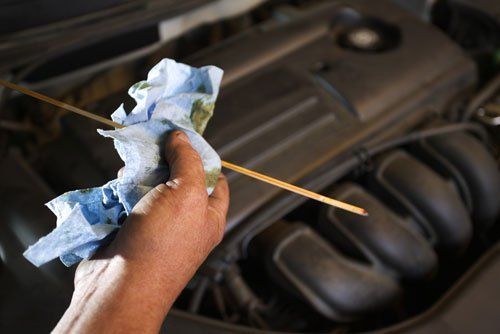 A person is checking the oil level of a car with a dipstick.