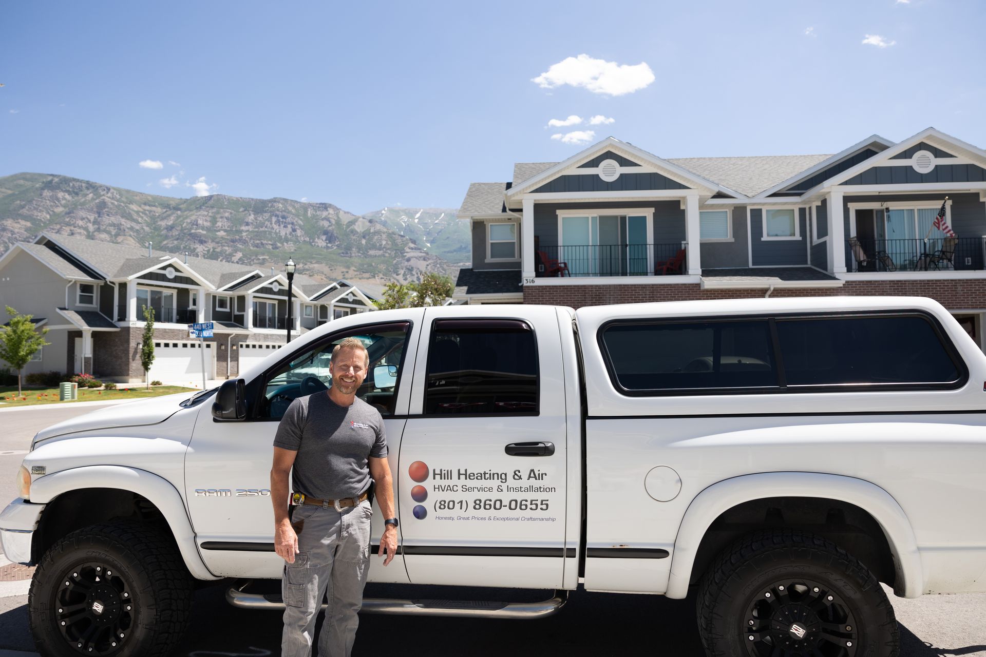 A man is standing next to a white truck in front of a house.