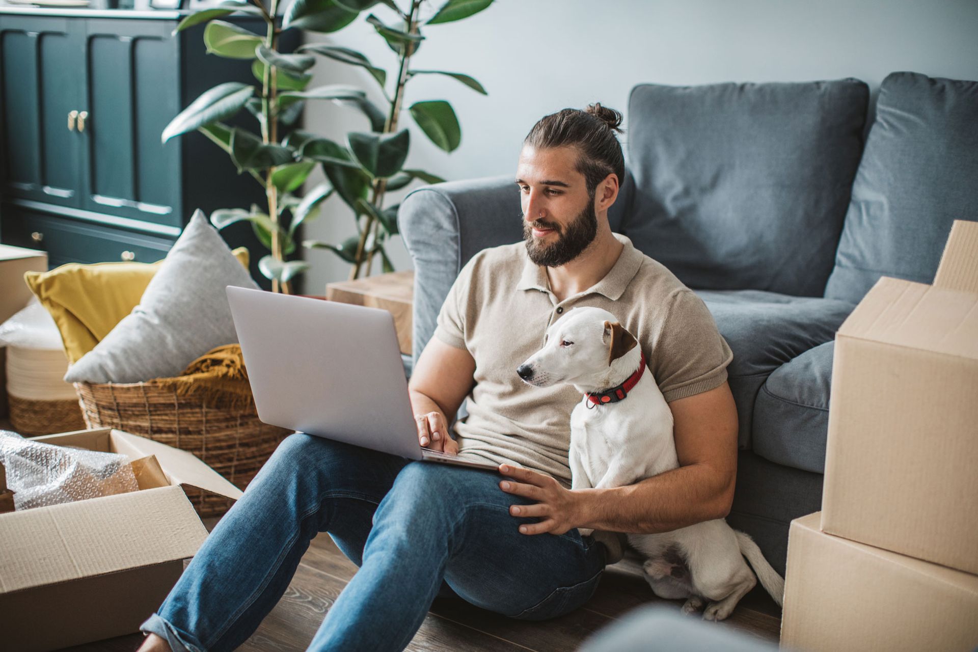 A Man Is Sitting On The Floor With His Dog And Using A Laptop — Dallas, TX — Misteli Law Firm