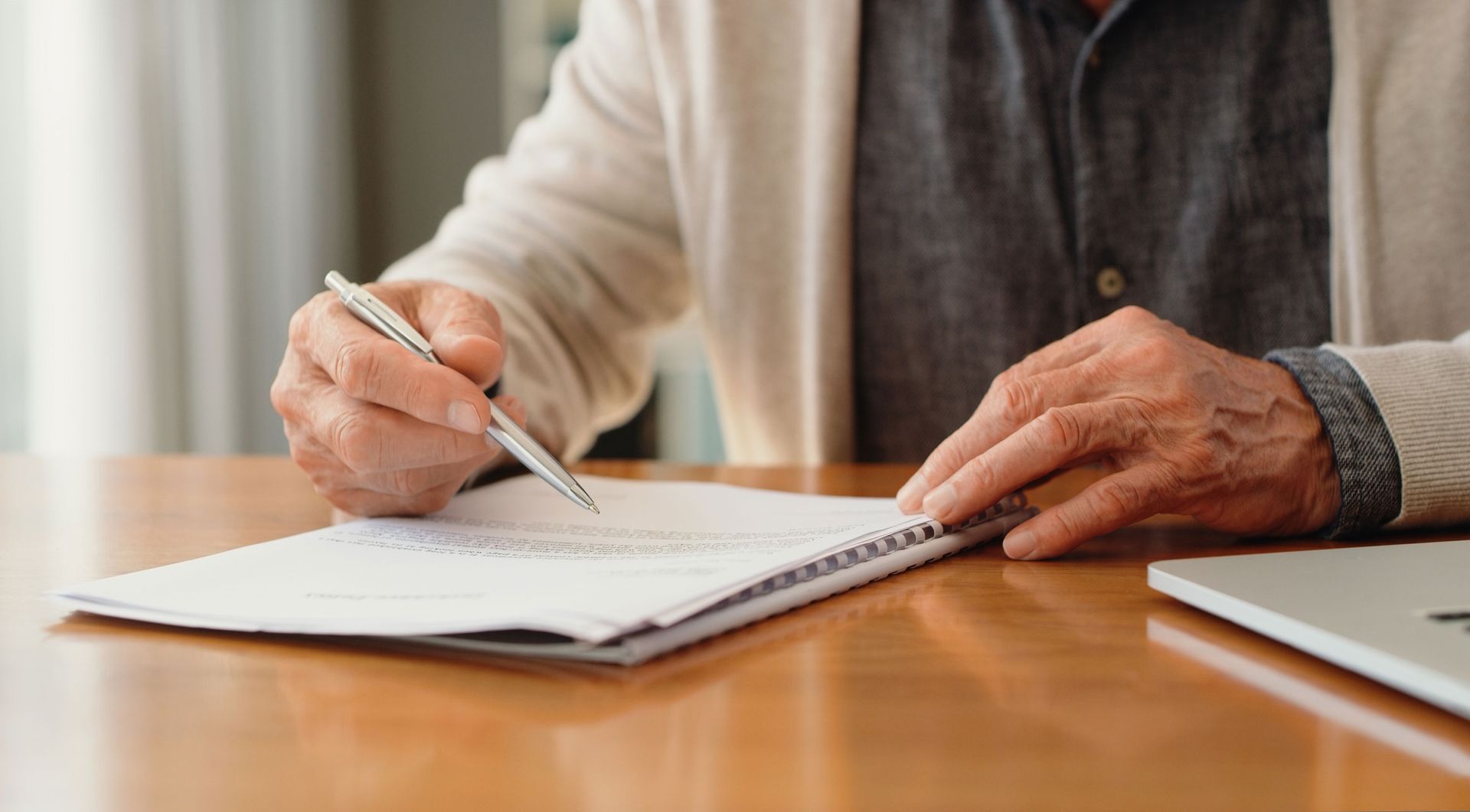 A Man Is Sitting At A Table Writing In A Notebook With A Pen — Dallas, TX — Misteli Law Firm