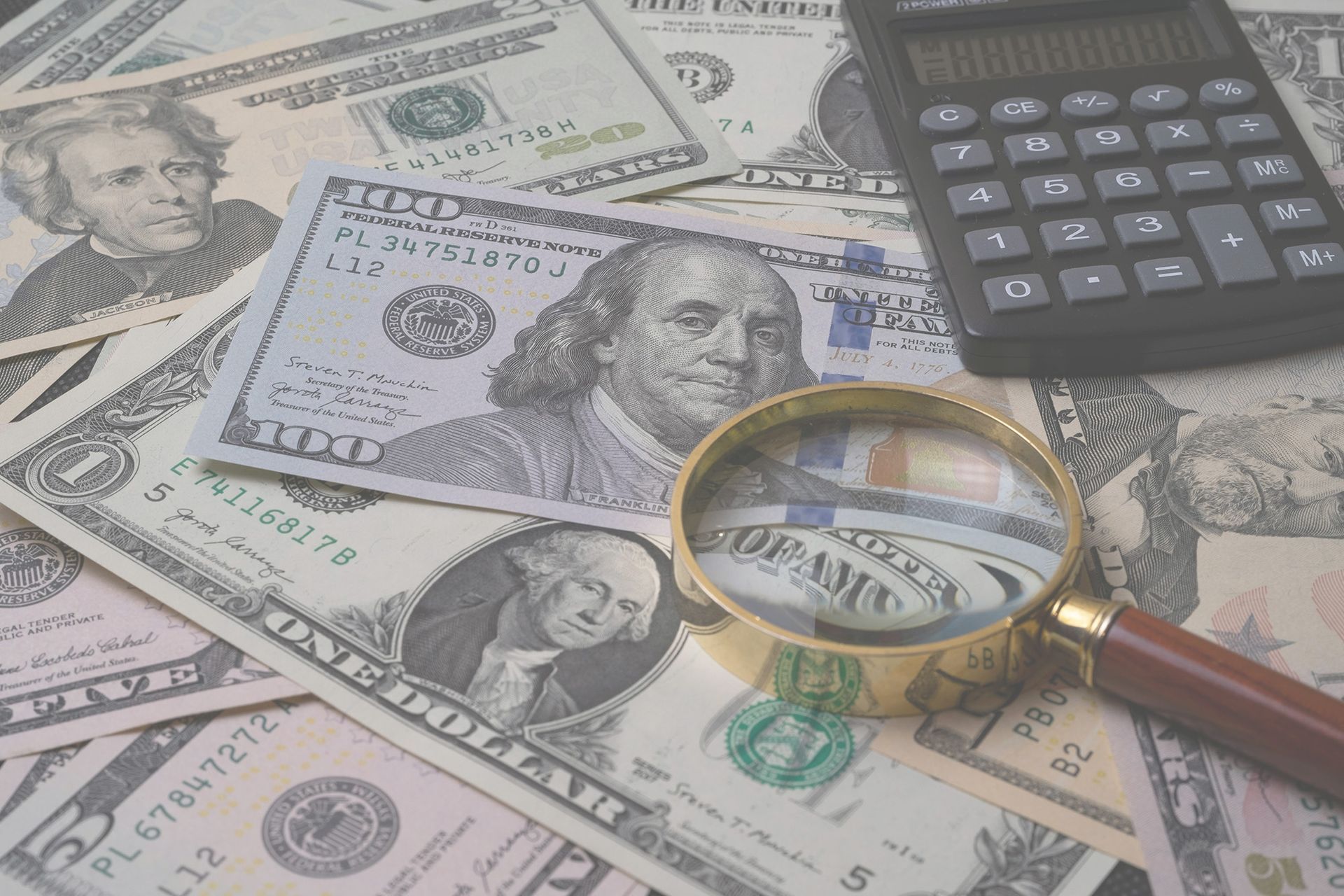 image of cash bills, a calculator, and a magniying glass