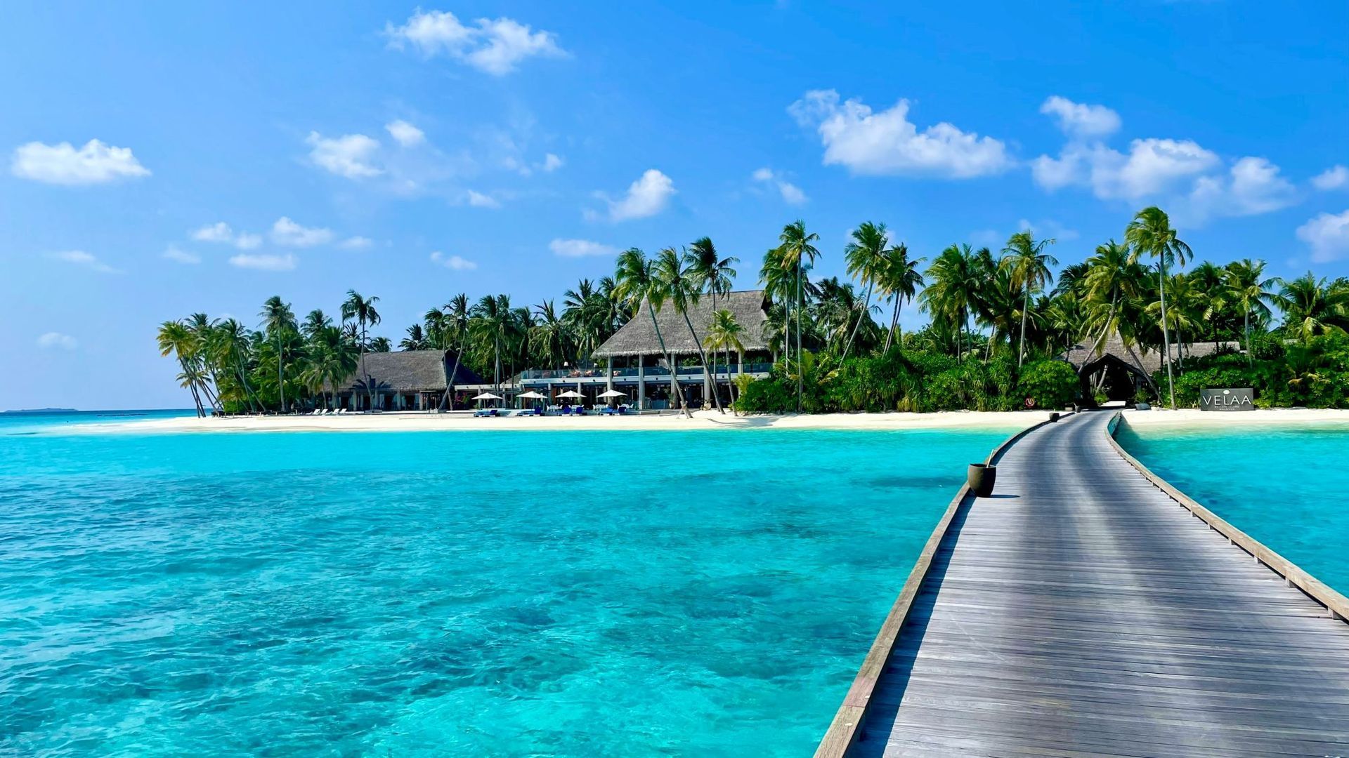 wooden walkway leading to tropical island surrounded by clear  blue water