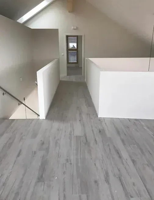 Un couloir avec du parquet et des escaliers dans une maison.