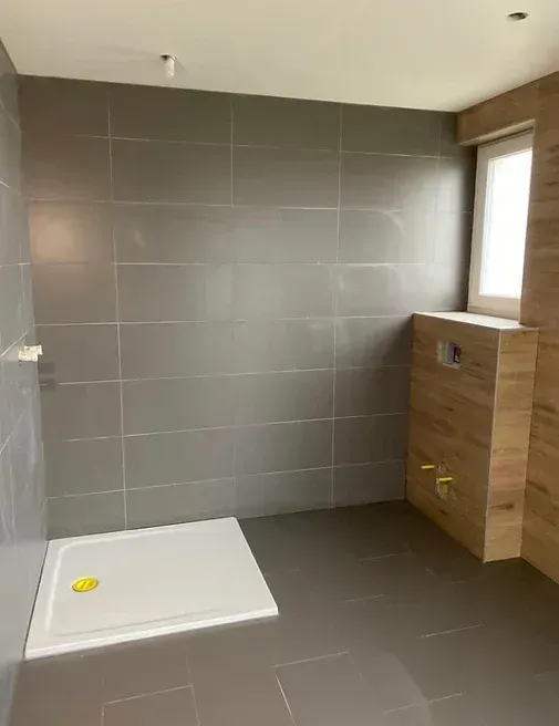 Une salle de bain avec douche à l'italienne et fenêtre.