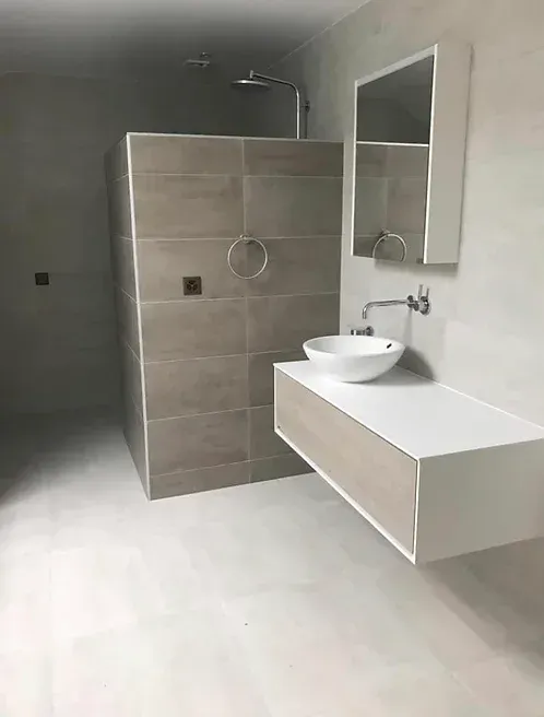 Une salle de bain avec lavabo, miroir et douche à l'italienne.