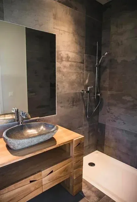 Une salle de bain avec lavabo, miroir et douche.