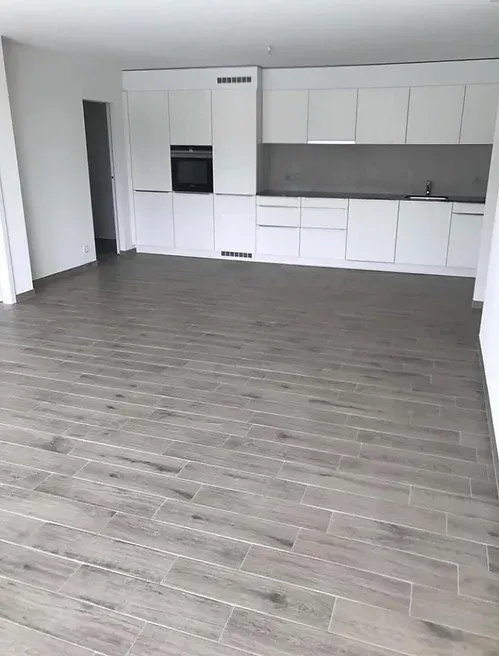 Une cuisine vide avec des armoires blanches et un plancher en bois.