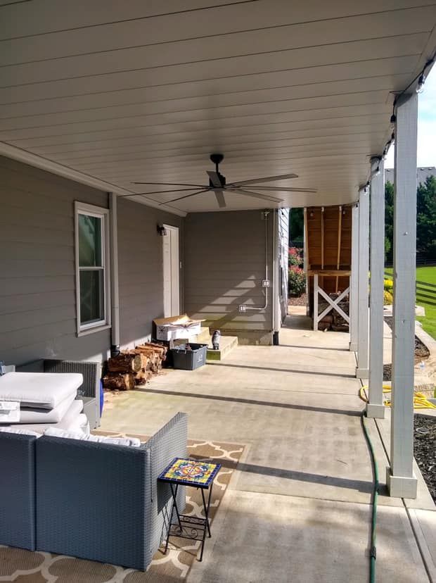 There is a ceiling fan on the porch of a house.