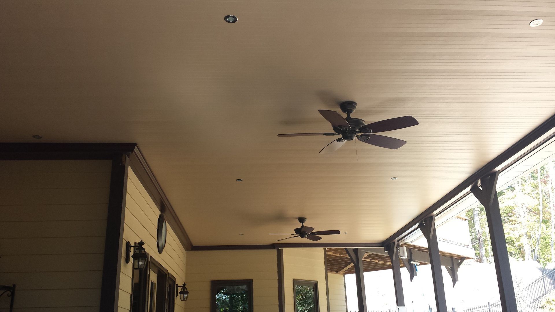 A ceiling fan is hanging from the ceiling of a porch.