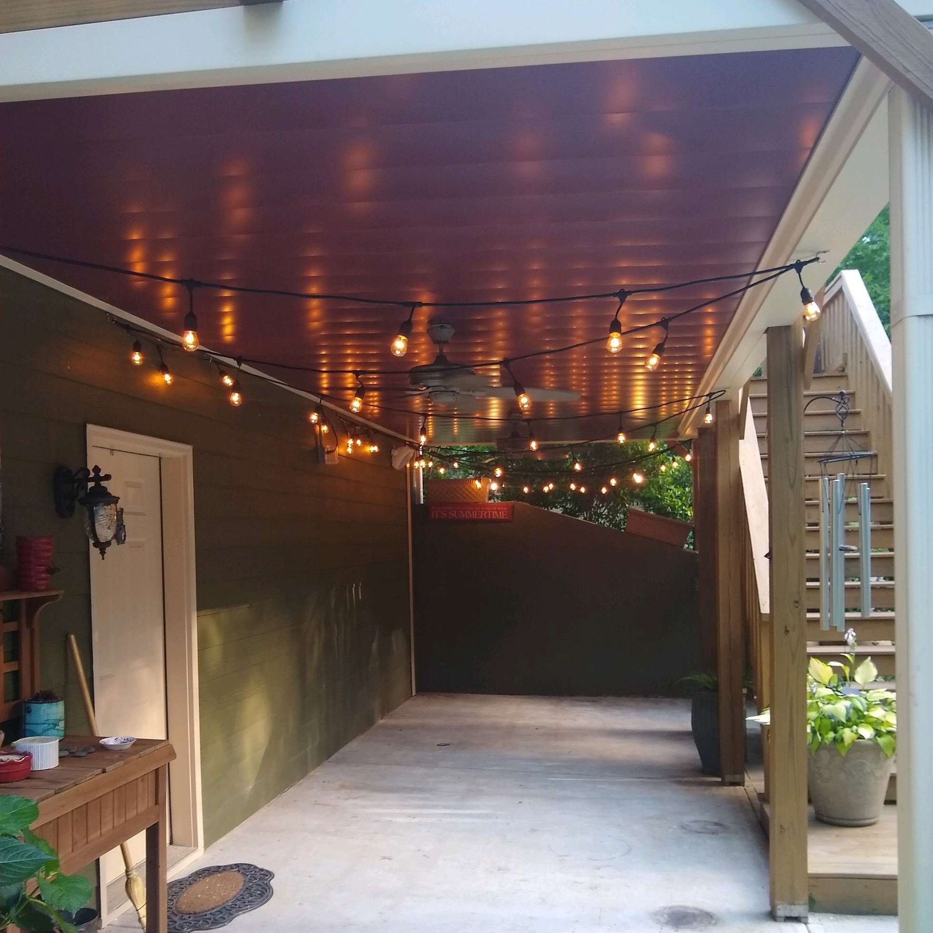 A covered walkway with a string of lights hanging from the ceiling