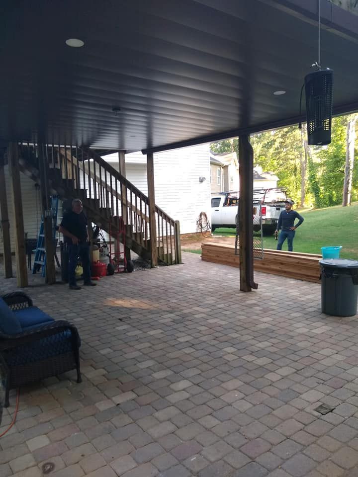 A man is standing on a patio under a covered patio with stairs.