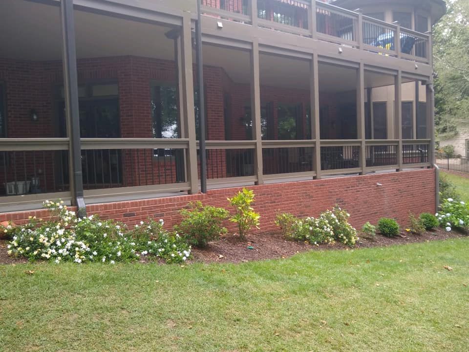 A house with a screened in porch and a brick wall.