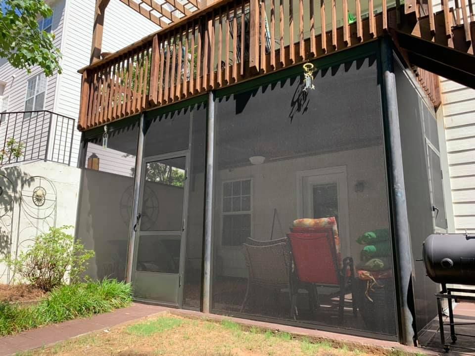A screened in porch with a grill and chairs on it