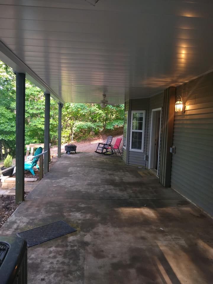 There is a porch with a ceiling fan and chairs on it.