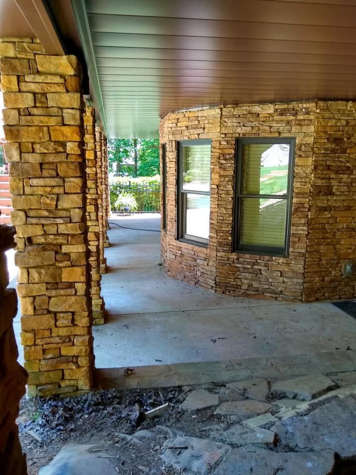 A brick building with a porch and two windows.