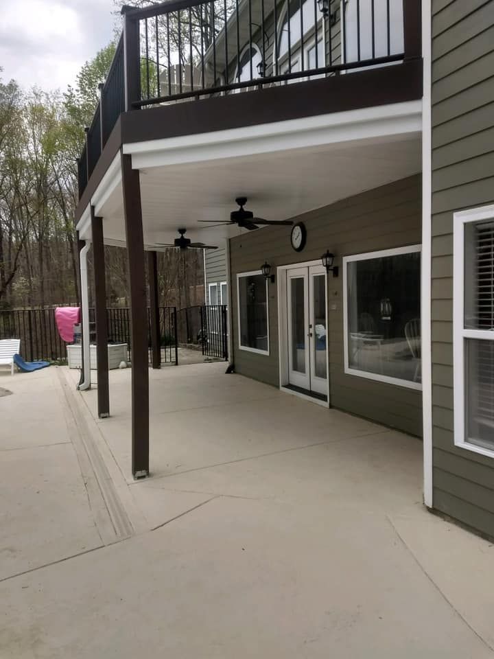 A large patio with a balcony and a ceiling fan on the side of a house.