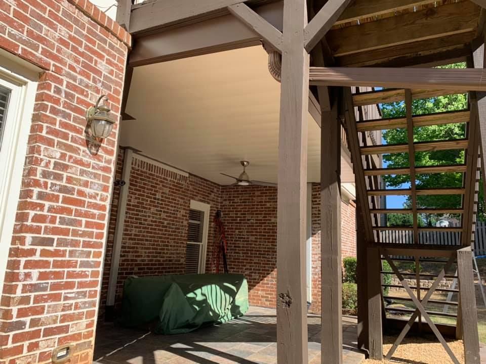 A brick house with a wooden deck and stairs.