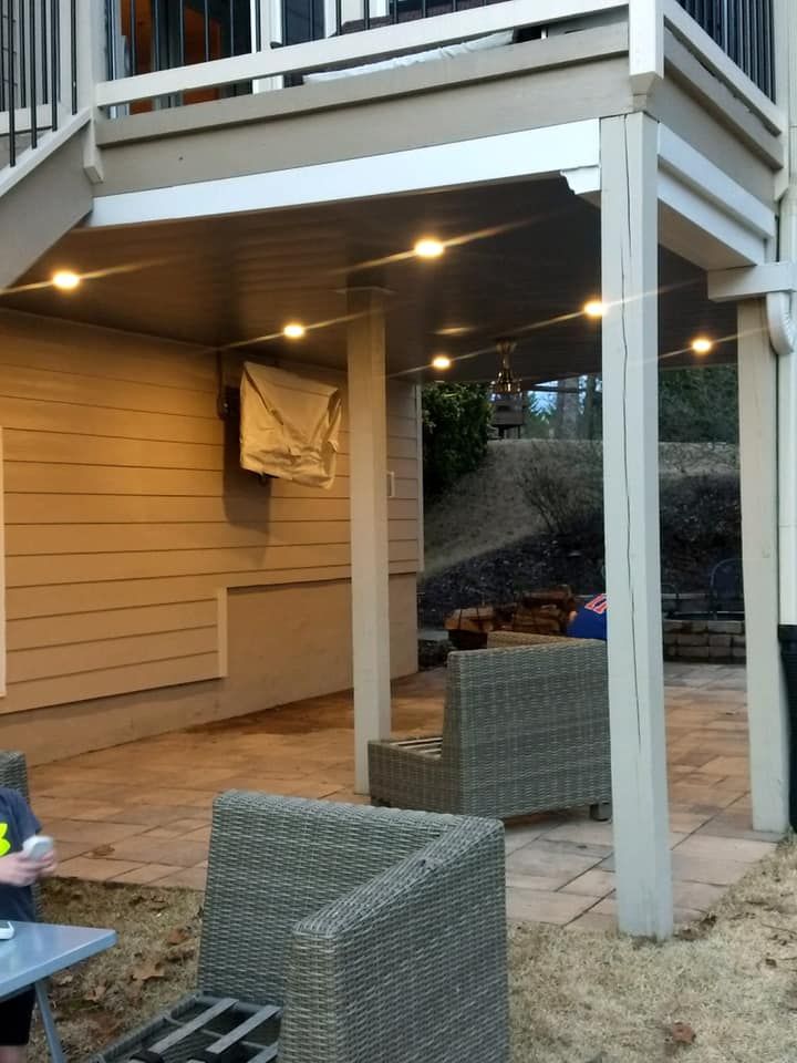 A patio with a table and chairs under a deck.