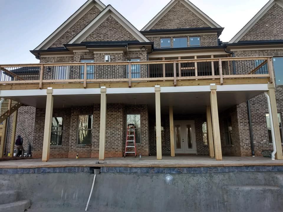 A large brick house with a wooden deck overlooking a swimming pool.