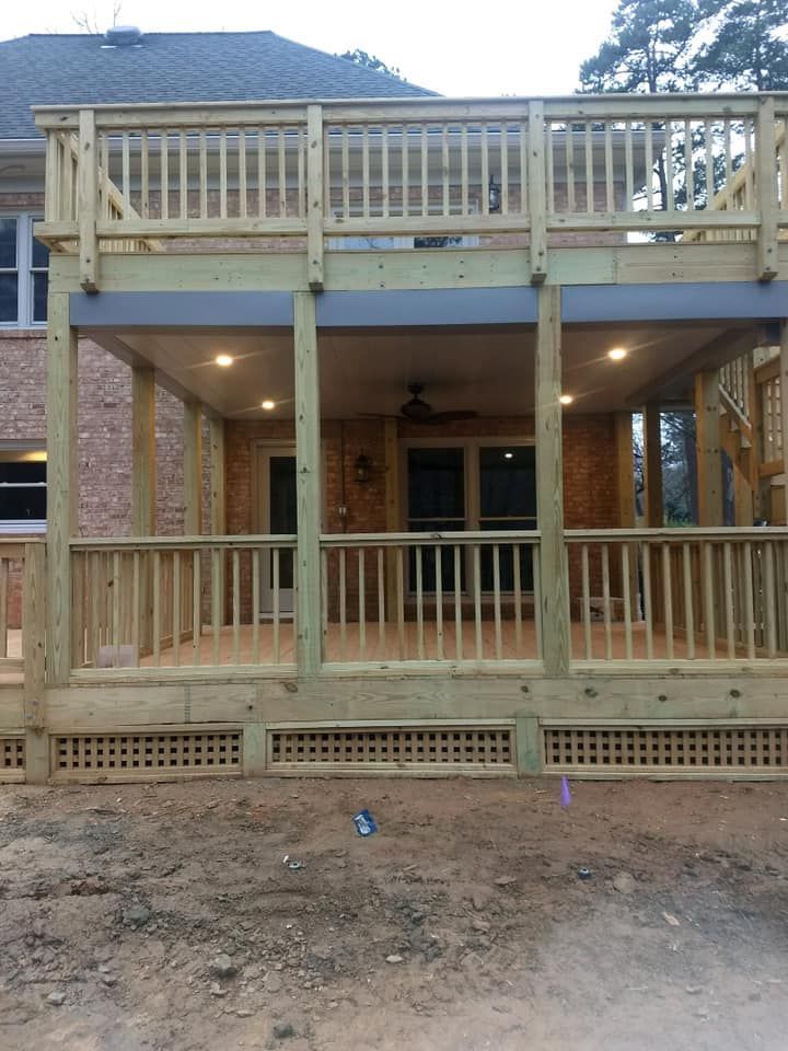 A large wooden deck with a brick house in the background