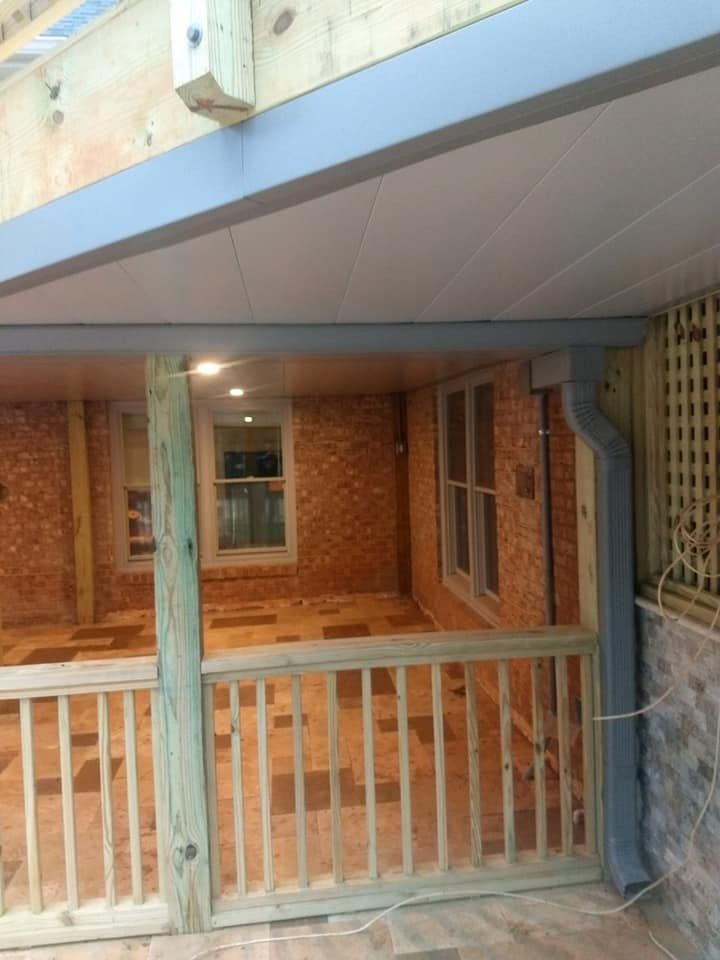 A porch with a wooden railing and a brick wall