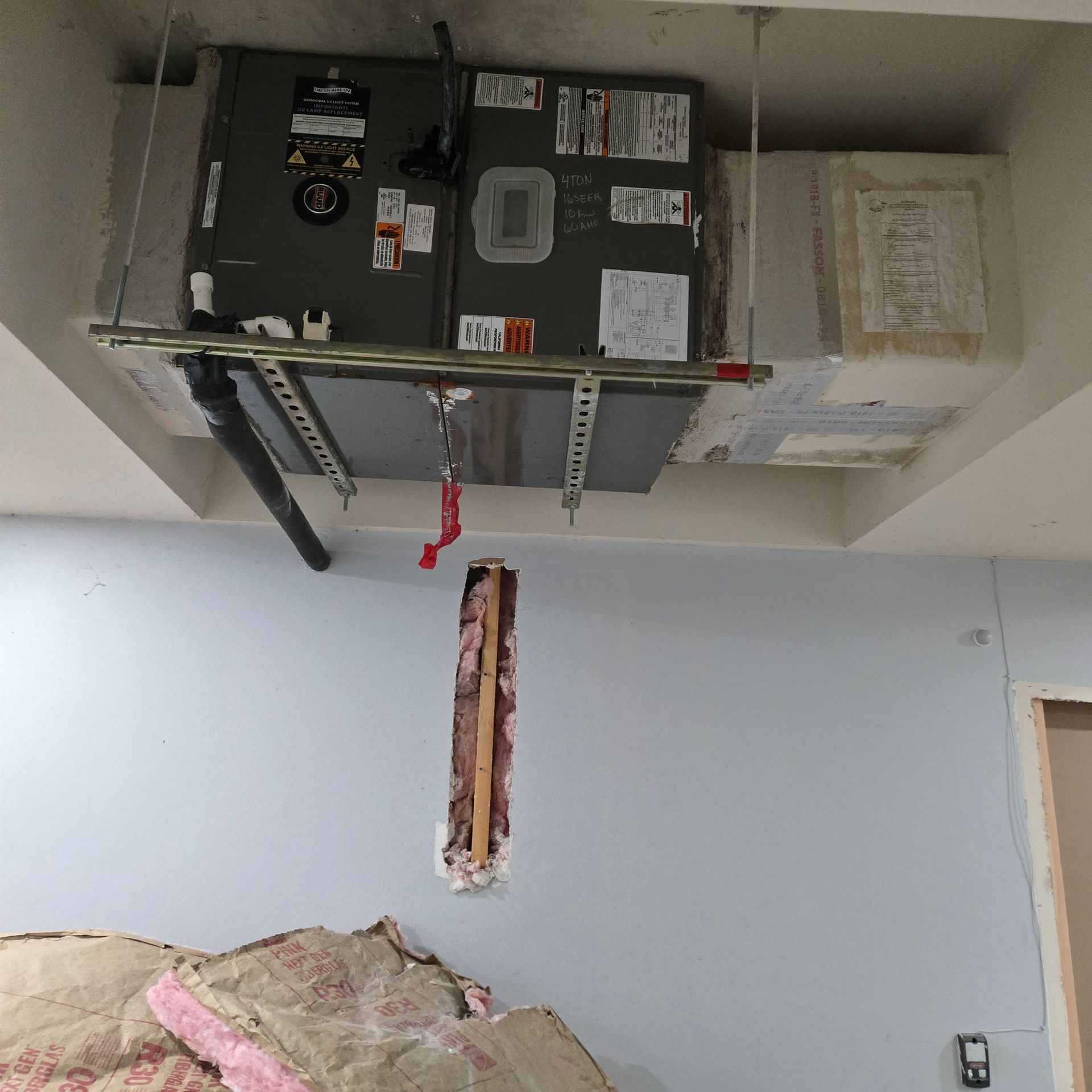 HVAC unit attached to ceiling, showing ductwork, insulation, and some discoloration.