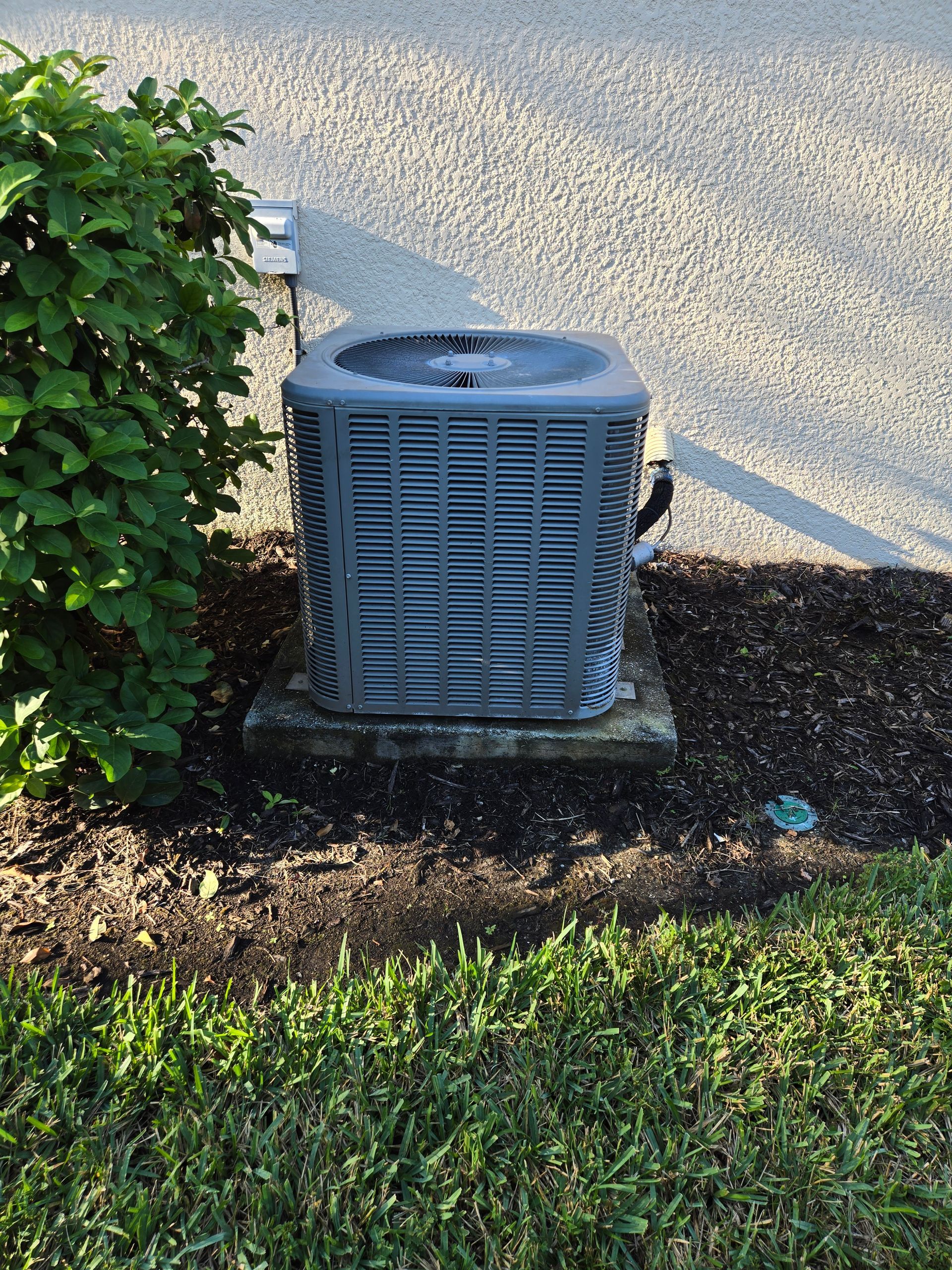 HVAC unit suspended from ceiling in a garage. Ductwork, filter, and water heater are visible.