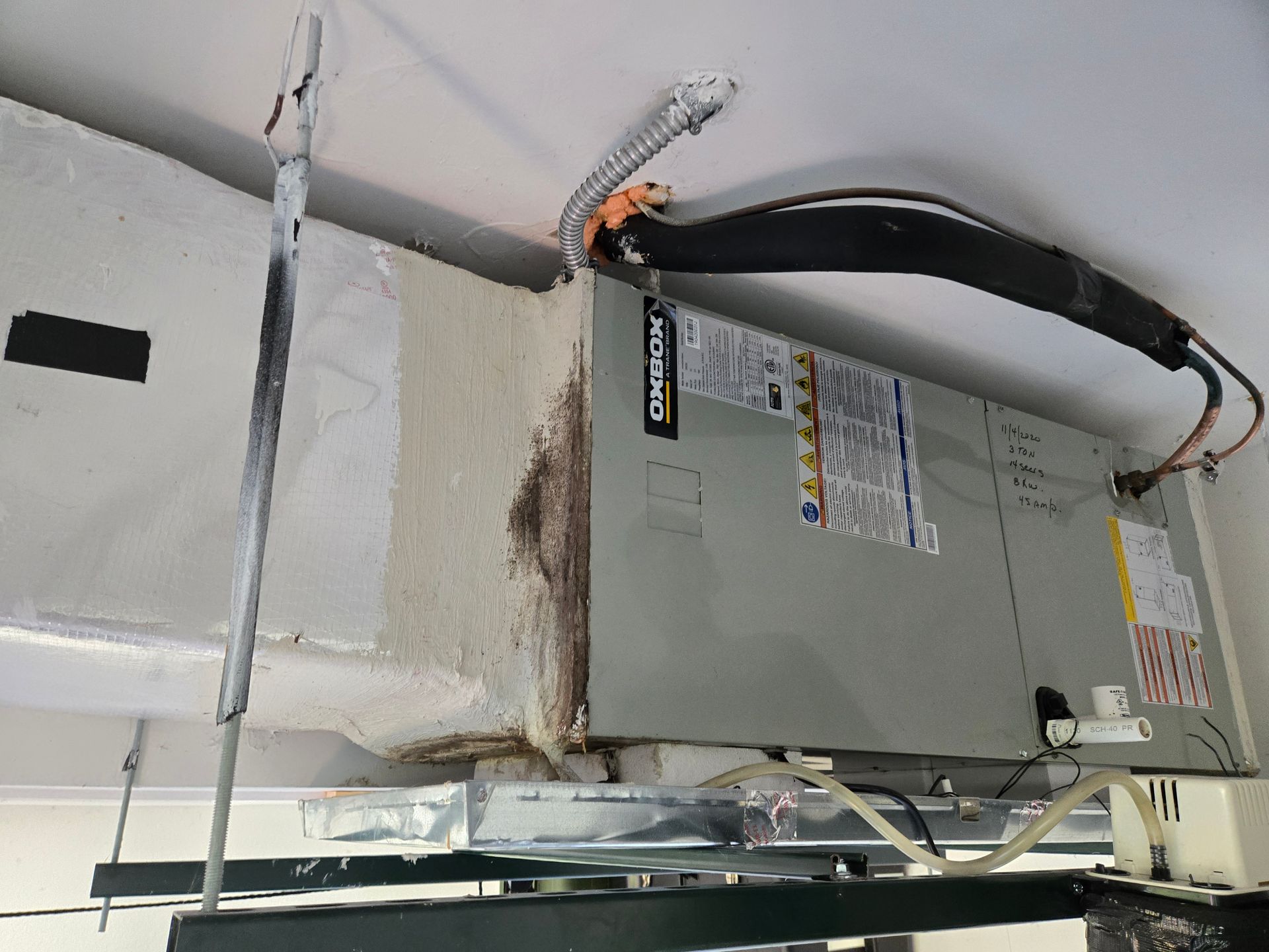 HVAC unit attached to ceiling, showing ductwork, insulation, and some discoloration.